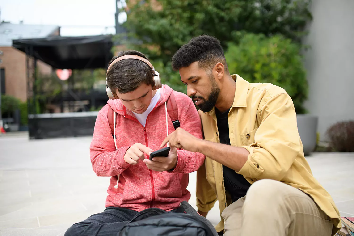 A young man with down syndrome is using his phone while with his support provider